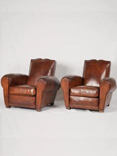 two brown leather chairs sitting next to each other