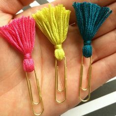 three small tassels in different colors on a person's hand