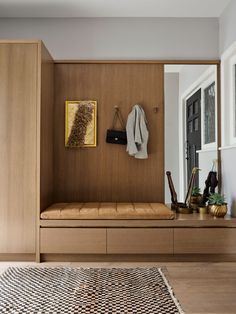 a wooden bench sitting in the middle of a living room next to a wall mounted coat rack