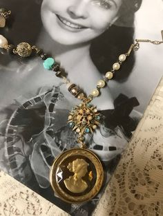 This is a vintage assemblage upscaled cameo necklace. I started with a vintage gold tone to yellow iridescent cameo and added it to a tiny Sunburst pin, which I upscaled.  It was missing some sets so I did replace them with different faux pearls and turquoise rhinestones. It does not have all of the exact pattern of stones that it started with but it still looks great !  On one side of the necklace is some vintage faux pearl rosary beads combined with different gold tone chains. The opposite sid Unique Gold Necklaces From Vintage Collection, Unique Gold Vintage Necklace, Heirloom Handmade Vintage Necklace, Unique Gold Jewelry For Vintage Events, Unique Vintage Style Medallion Necklace, Vintage Antique Gold Necklace, Bohemian Gold Cabochon Necklaces, Unique Medallion Necklace From Vintage Collection, Unique Vintage Charm Necklaces