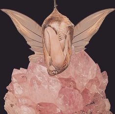 a fairy sitting on top of pink crystals