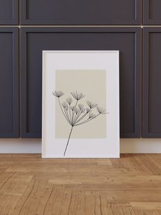 a black and white photo of a dandelion on a wood floor in front of gray cabinets