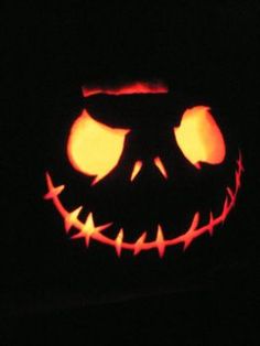 a carved jack o lantern in the dark with its eyes glowing orange and black at night