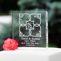 a glass block with a pink flower on it sitting on top of a white cake