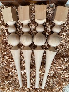 six wooden spoons are lined up in a pile of wood shavings on the floor