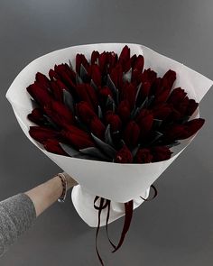 a bouquet of red tulips is being held by a woman's hand