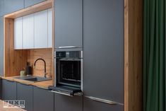 a kitchen with gray cabinets and wooden counter tops, along with a black stove top oven