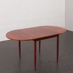 a wooden table sitting on top of a black floor next to a white walled wall