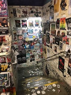 a room filled with lots of posters and stickers on the wall next to stairs