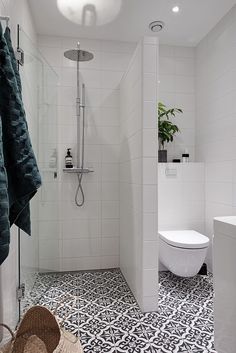 a white bathroom with black and white floor tiles on the shower, toilet and bathtub