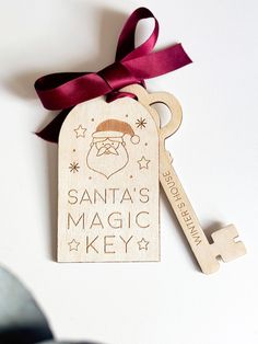 a wooden key tag with a santa's magic key on it and a red ribbon