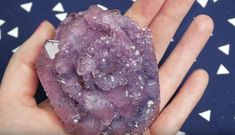 a person holding a rock in their hand with purple crystals on it's fingers