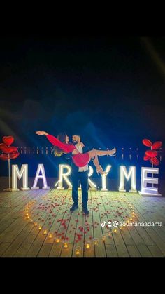 a man and woman dancing on stage in front of the mardyme sign at night