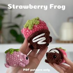 two small crocheted strawberries are being held up