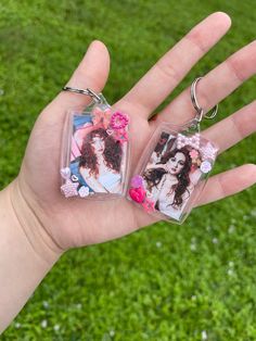 a person holding two key chains in their hand with pictures on them and flowers around the edges