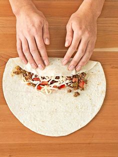 a person making a tortilla on top of a wooden table