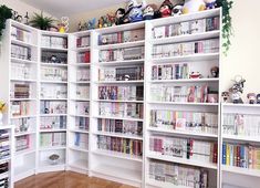 a white bookcase filled with lots of books on top of a hard wood floor