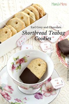 shortbread tea bag cookies in a cup on a saucer next to a box of chocolate