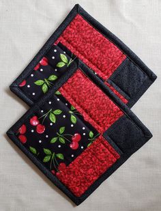 two red and black patchwork placemats with cherries on them, sitting on a white surface