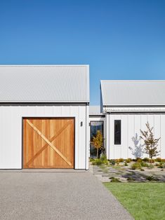 two white barns with wooden doors on the front and side of them, one is empty