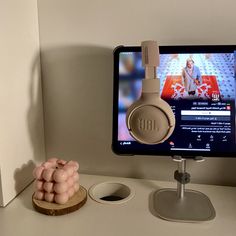 a computer monitor with headphones on it next to an earphone holder in front of the monitor