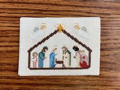 a cross stitch nativity scene on a wooden table