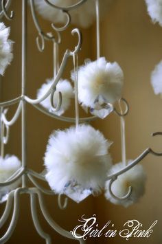 several white pom - poms hanging from a metal rack in a room with beige walls