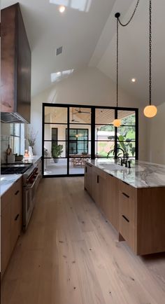 an open kitchen with wooden floors and white walls, along with glass doors leading to the outside