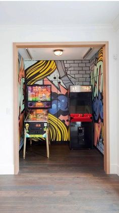 an open door leading into a room with graffiti on the walls and wood flooring