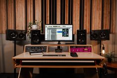 a computer monitor sitting on top of a wooden desk next to speakers and a keyboard