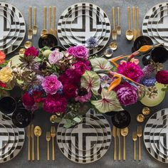 a table topped with plates and flowers on top of each other next to gold utensils