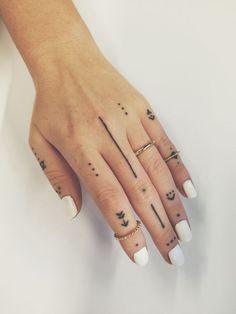 a woman's hand with three different tattoos on her fingers and one has an arrow