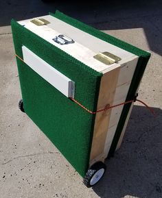 a green and white box sitting on top of a cement floor next to a car