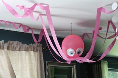 a pink octopus hanging from the ceiling in a room with stars and streamers on it