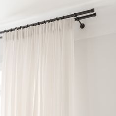 a white curtain with black metal rods hanging from it's side