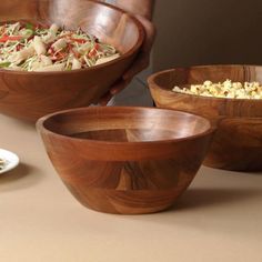 three wooden bowls filled with food on top of a table