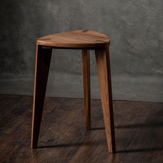 a wooden stool sitting on top of a hard wood floor next to a gray wall