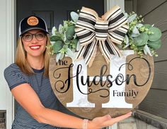 a woman holding up a wooden sign that says the hudson family