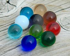 several different colored glass balls sitting on top of a wooden table