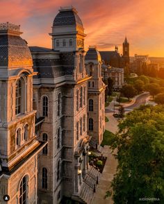 an aerial view of a large building with many windows and towers in the background at sunset