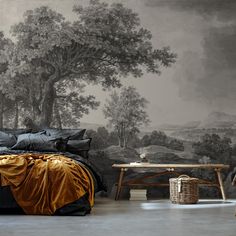 a bed sitting under a painting next to a table with a basket on top of it