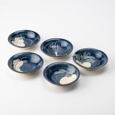 four blue bowls with white designs on them