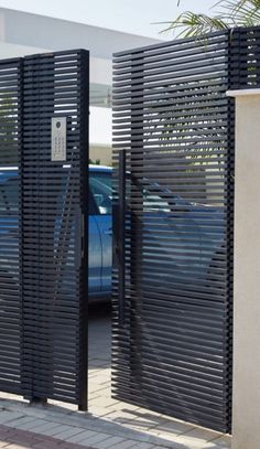 two cars are parked in the parking lot behind black gates with slats on them