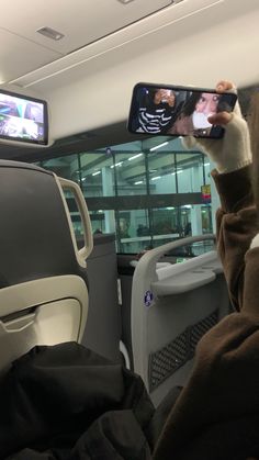 a person taking a selfie in the back seat of an airplane with their cell phone