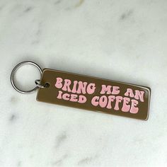 a keychain that says bring me an iced coffee with pink lettering on it