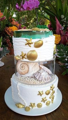 a three tiered cake with shells and seashells on it's side