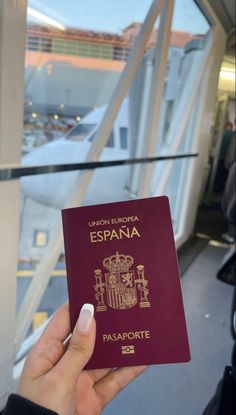 a person holding up a passport in front of a window