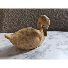 a wooden duck sitting on top of a marble counter next to a gray stone wall