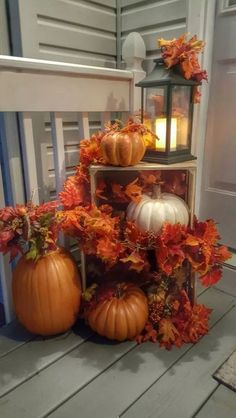 three pumpkins and two lanterns on a porch