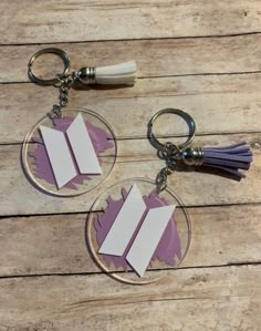 two purple and white book key chains with tassels